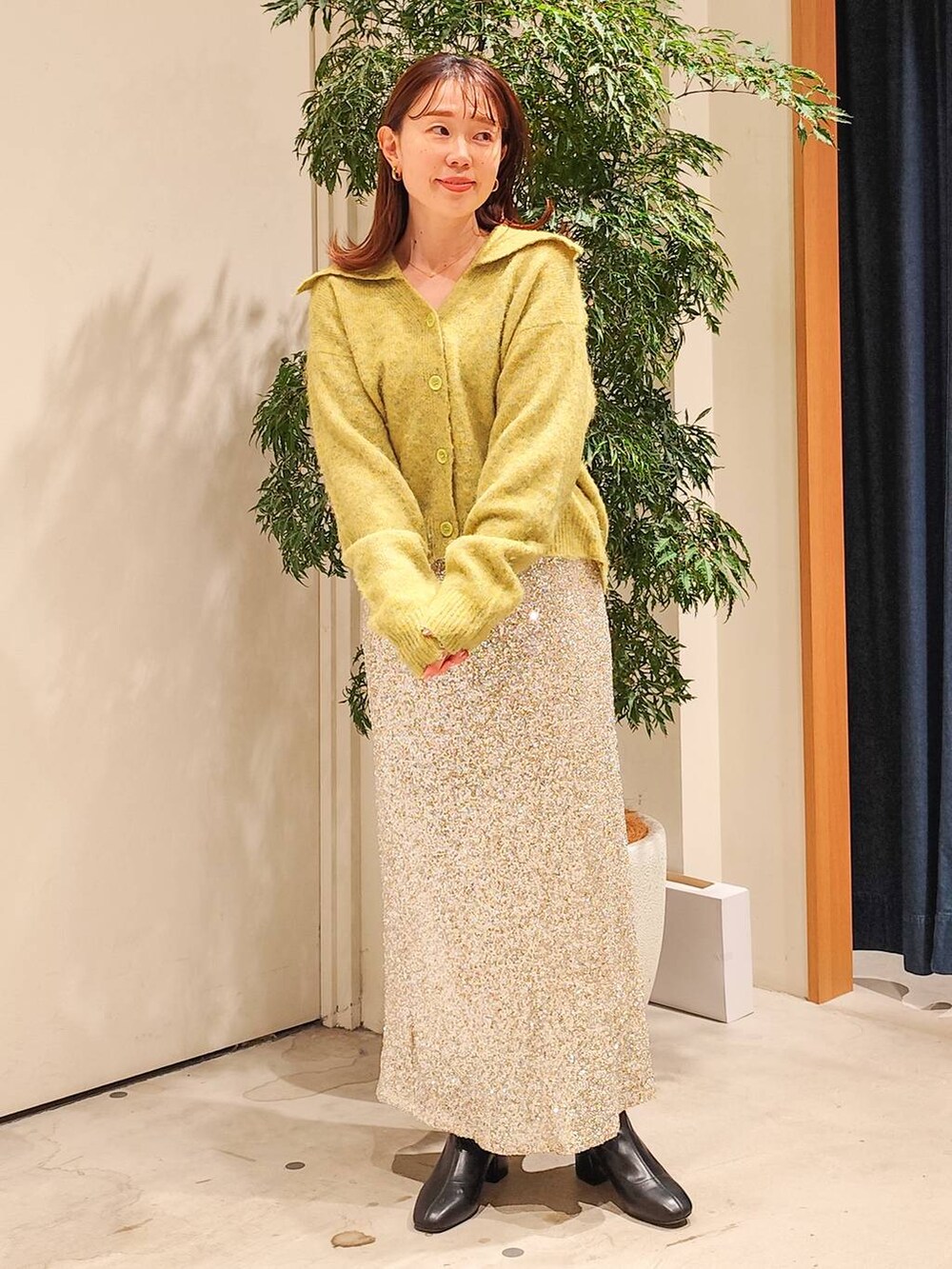 ブラック系のブーツ、ベージュ系のスカート、イエロー系のニット/セーターを着用したレディースの秋コーディネートの3枚目の写真