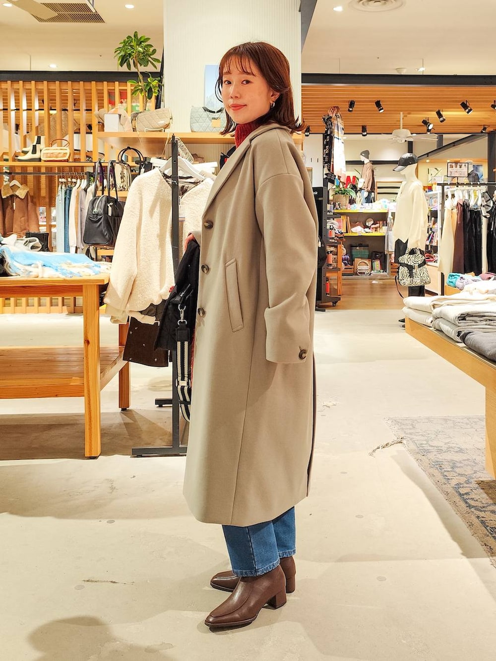 ブラック系のショルダーバッグ、グレー系のチェスターコート、ブルー系のデニムパンツを着用したレディースの冬コーディネートの5枚目の写真