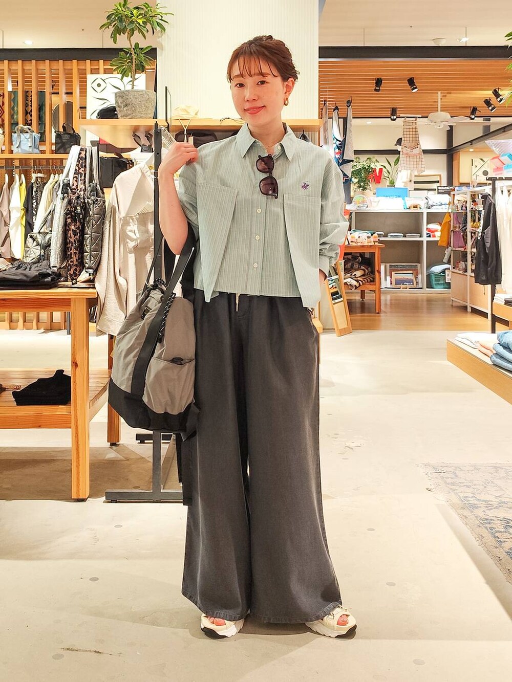 グリーン系のシャツ/ブラウス、グレー系のバックパック/リュック、ホワイト系のサンダルを着用したレディースの春コーディネートの2枚目の写真