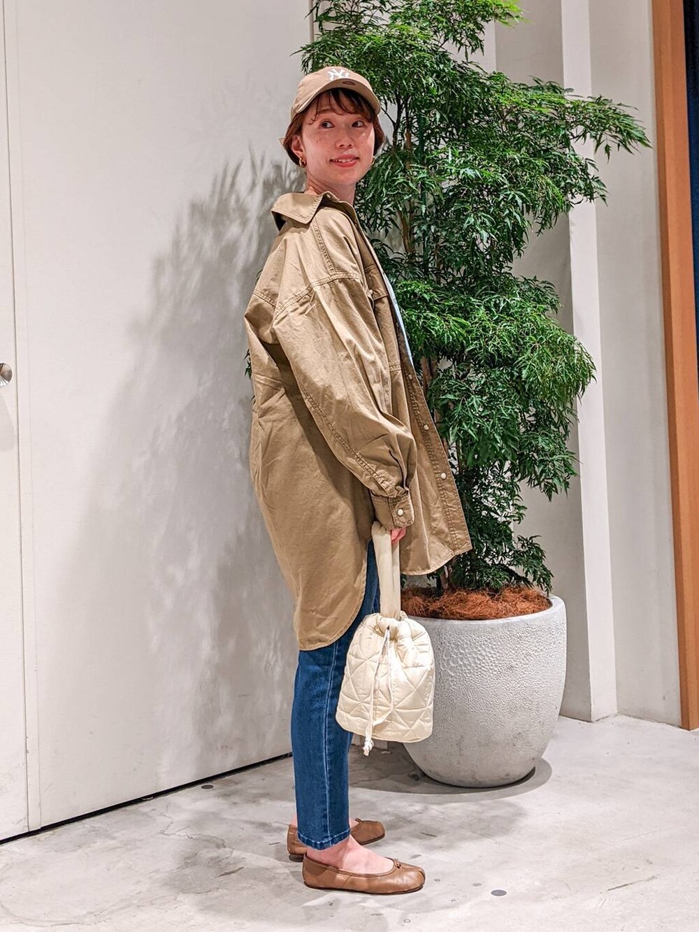 ブルー系のデニムパンツ、ベージュ系のショルダーバッグ、ブルー系のTシャツ/カットソーを着用したレディースの冬コーディネートの3枚目の写真