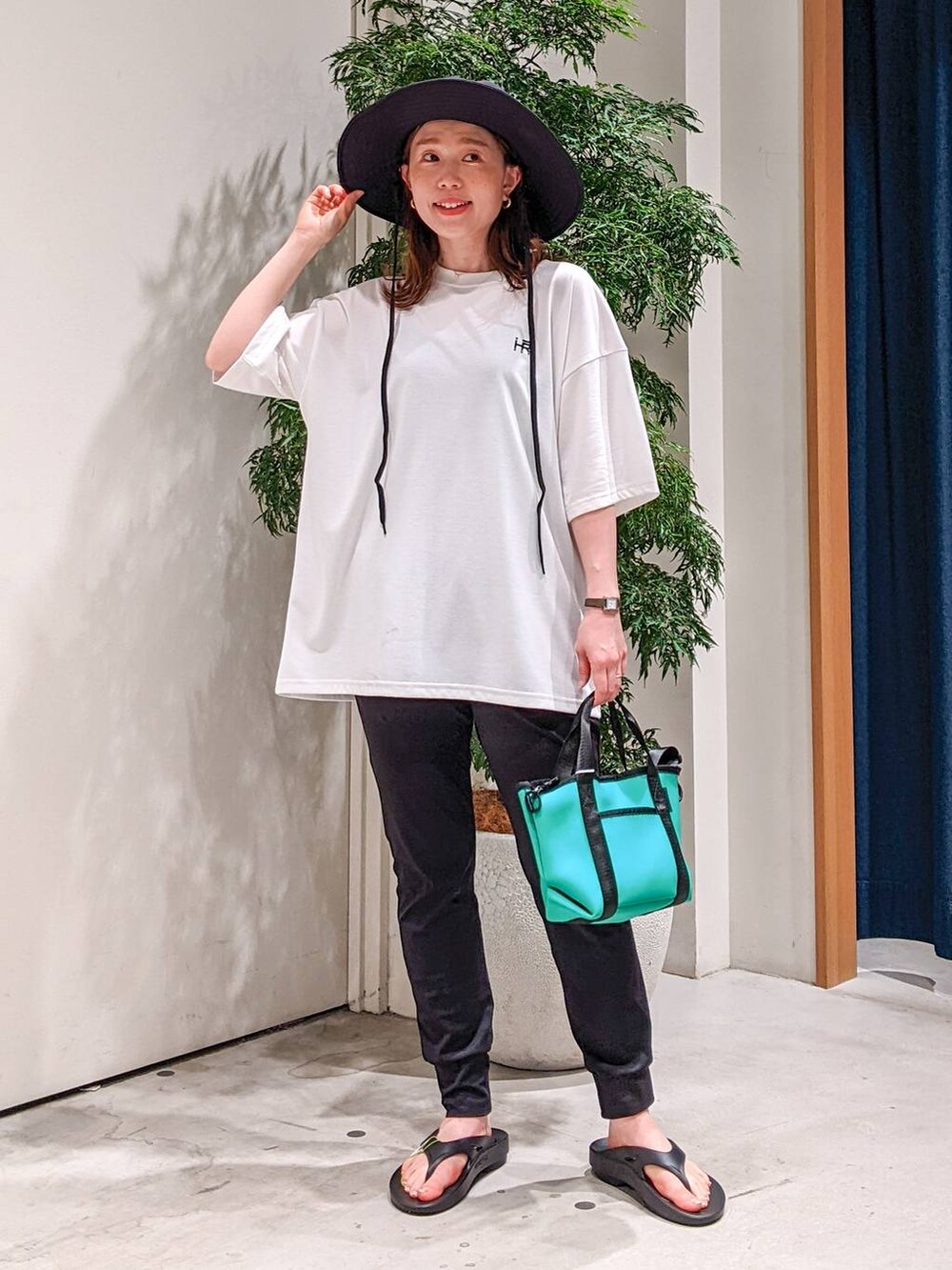 グリーン系のショルダーバッグ、ブラック系のその他パンツ、ホワイト系のTシャツ/カットソーを着用したレディースの春コーディネートの2枚目の写真