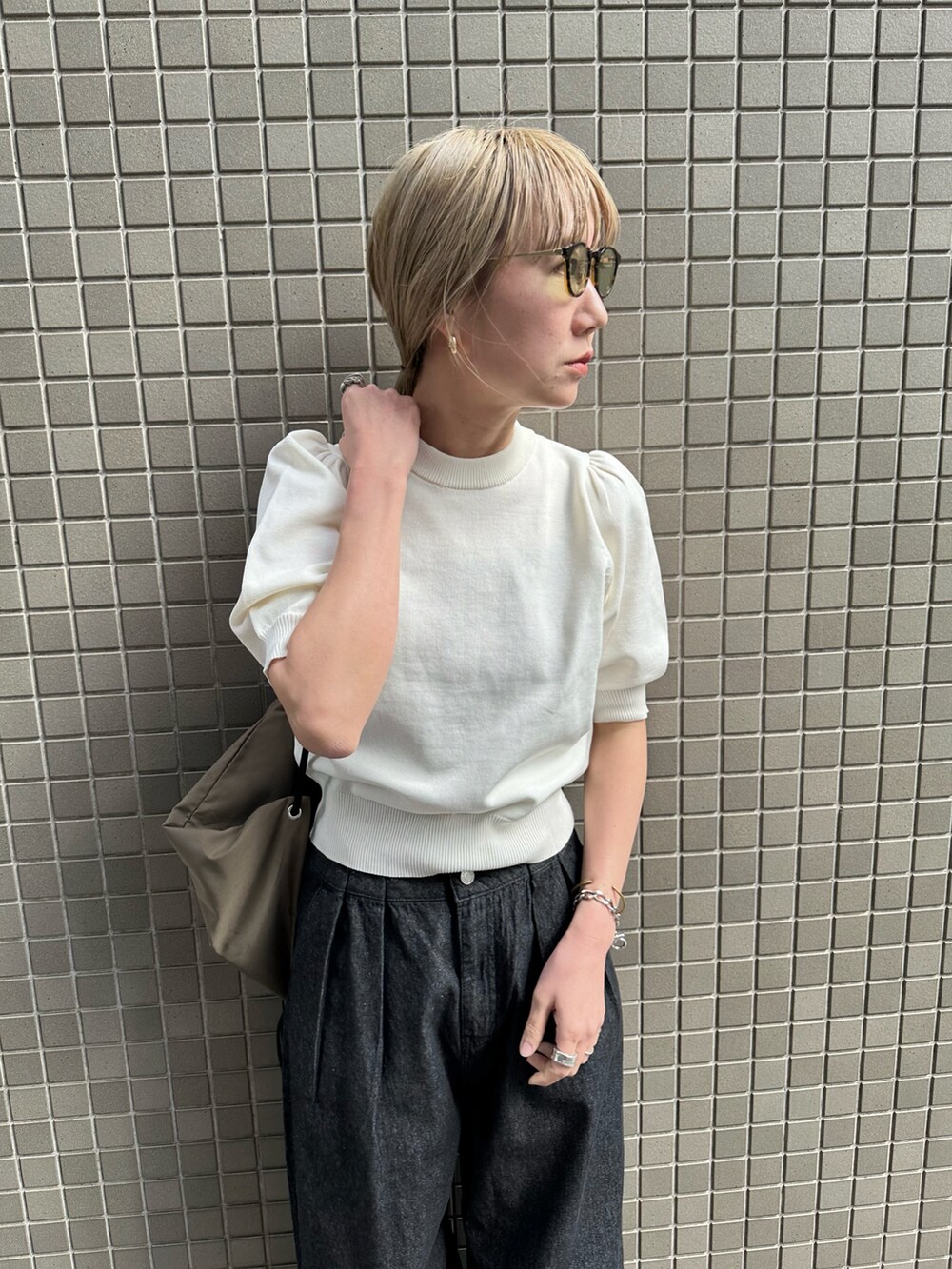 ホワイト系のニット/セーター、ブラック系のデニムパンツ、ブラック系のスニーカーを着用したレディースの春コーディネートの4枚目の写真