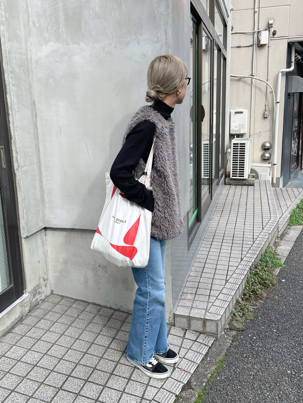 グレー系のベスト、ブラック系のニット/セーター、ブルー系のデニムパンツを着用したレディースの秋コーディネートの2枚目の写真
