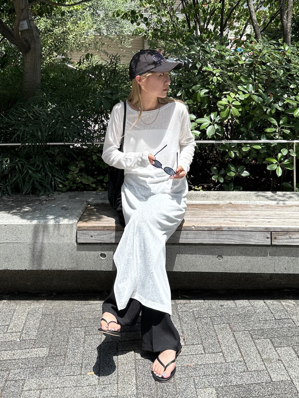 ホワイト系のワンピース、ブラック系のスラックス、ブラック系のサンダルを着用したレディースの夏コーディネートの3枚目の写真
