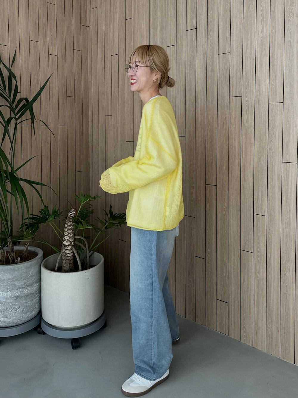 ホワイト系のスウェット、イエロー系のニット/セーター、ブルー系のデニムパンツを着用したレディースの春コーディネートの2枚目の写真