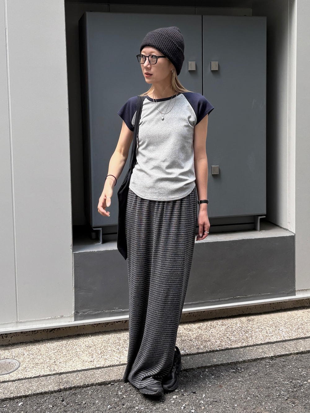 グレー系のスカート、ブルー系のTシャツ/カットソー、ブラック系のトートバッグを着用したレディースの夏コーディネートの2枚目の写真