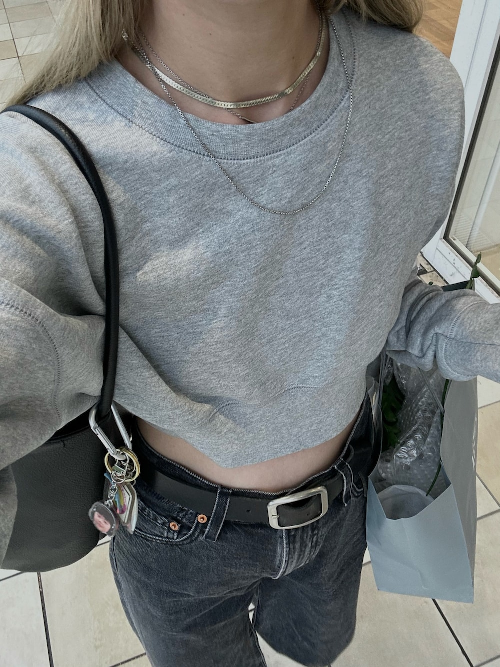 グレー系のスウェット、ブラック系のデニムパンツ、ブラック系のスニーカーを着用したレディースの秋コーディネートの3枚目の写真