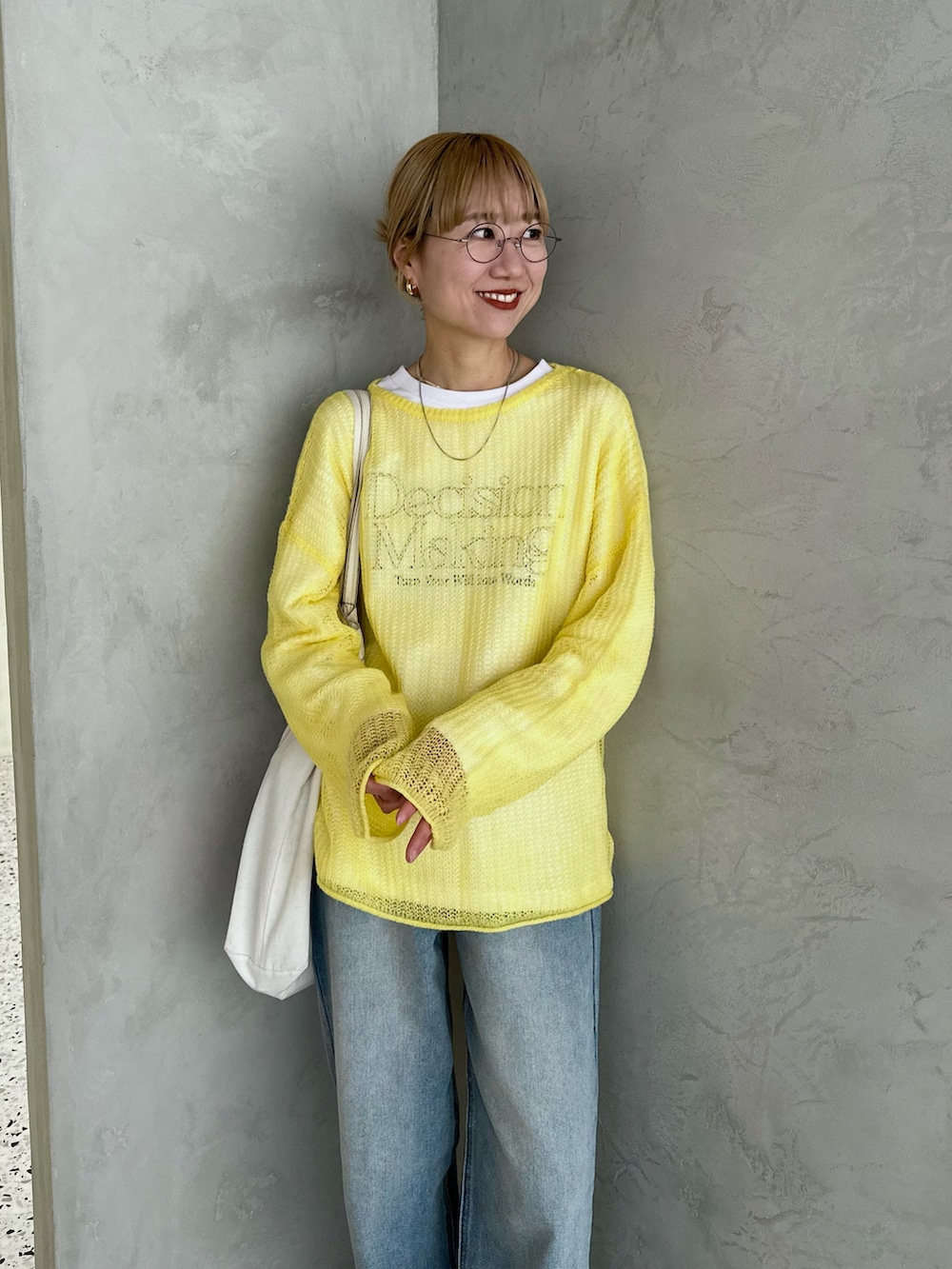 ホワイト系のスウェット、イエロー系のニット/セーター、ブルー系のデニムパンツを着用したレディースの春コーディネートの5枚目の写真