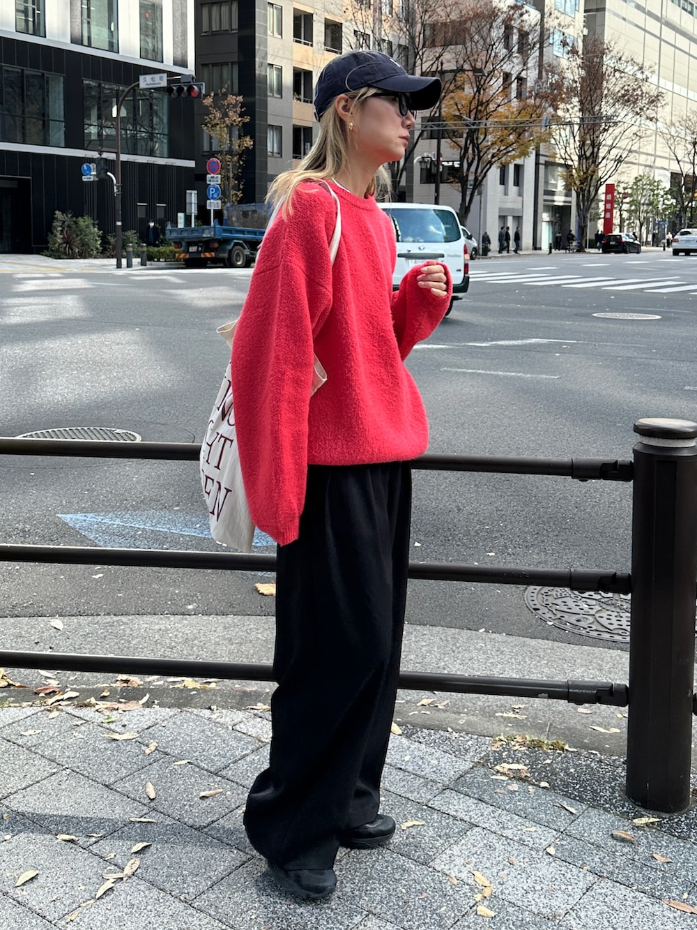 レッド系のニット/セーター、ホワイト系のTシャツ/カットソー、ブラック系のスラックスを着用したレディースの冬コーディネートの2枚目の写真