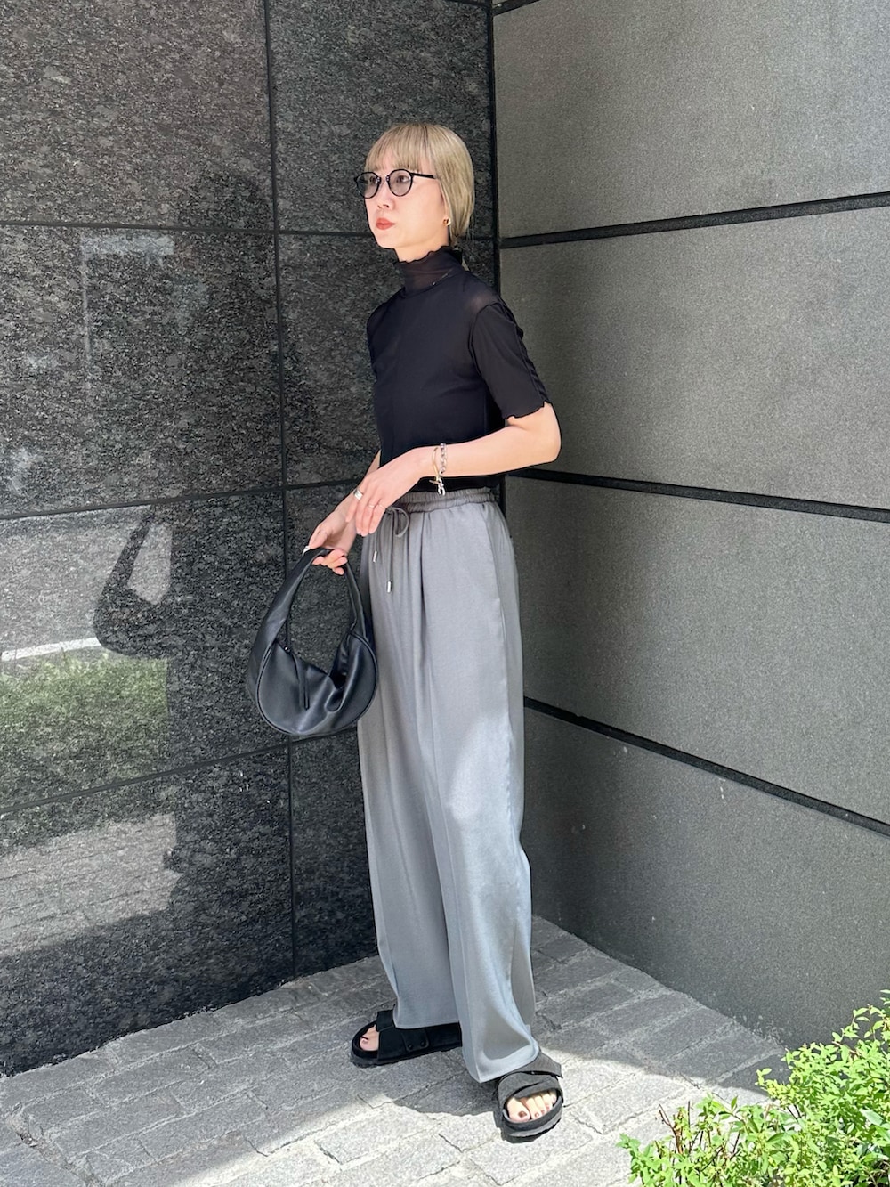 グレー系のスラックス、ブラック系のTシャツ/カットソー、ブラック系のハンドバッグを着用したレディースの夏コーディネートの4枚目の写真