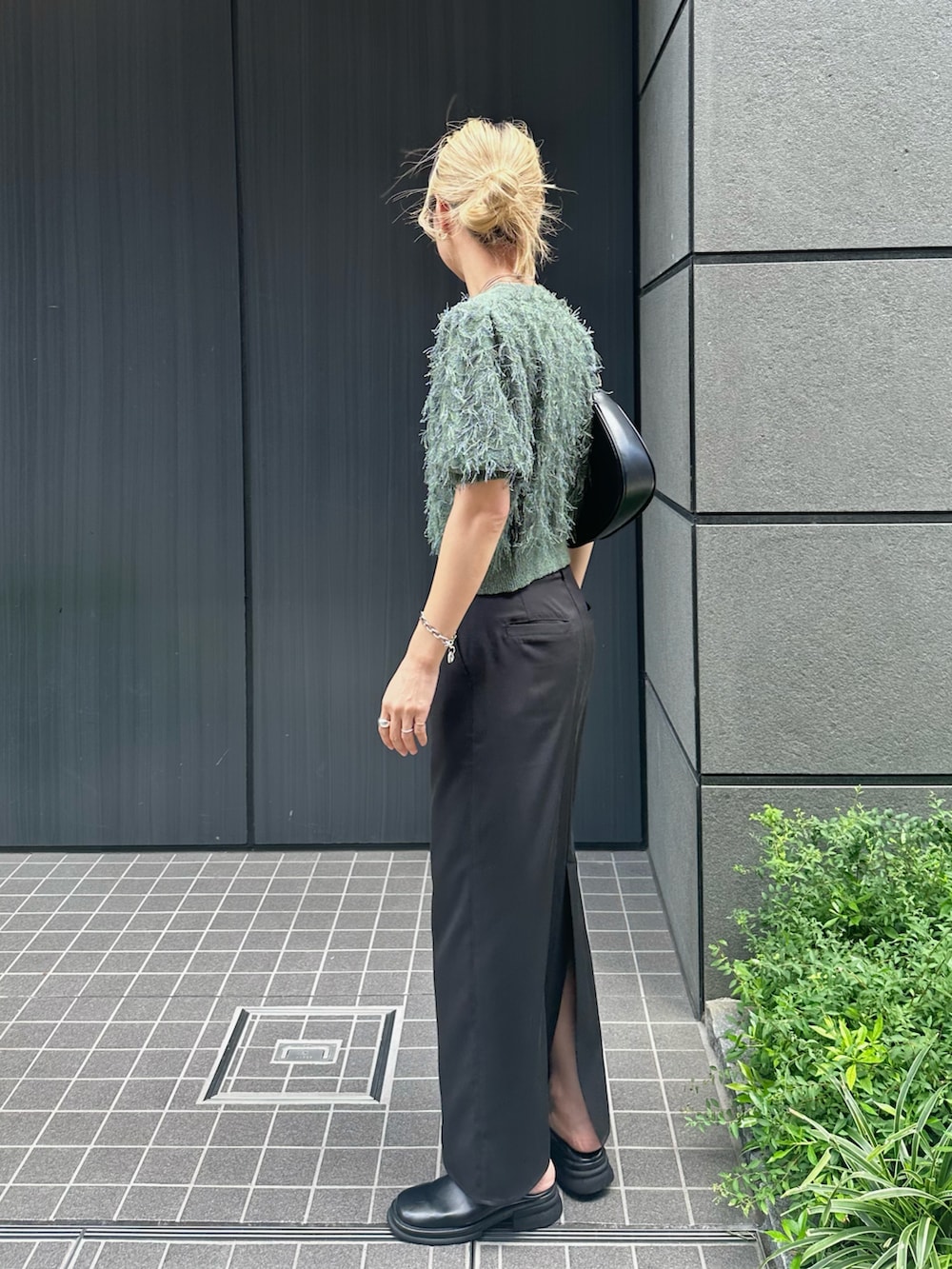 グリーン系のニット/セーター、ブラック系のスカート、ブラック系のスリッポンを着用したレディースの夏コーディネートの3枚目の写真