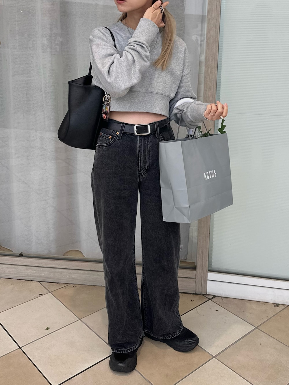 グレー系のスウェット、ブラック系のデニムパンツ、ブラック系のスニーカーを着用したレディースの秋コーディネートの2枚目の写真