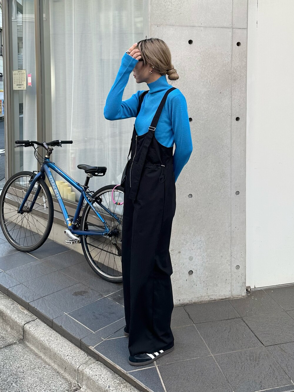 ブラック系のダウンジャケット/コート、ブルー系のニット/セーター、ブラック系のサロペット/オーバーオールを着用したレディースの秋コーディネートの3枚目の写真