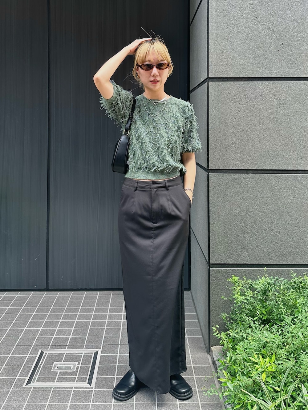 グリーン系のニット/セーター、ブラック系のスカート、ブラック系のスリッポンを着用したレディースの夏コーディネートの2枚目の写真