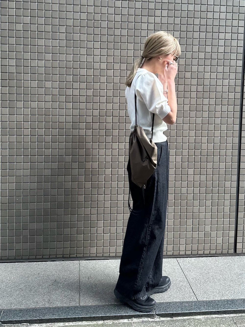 ホワイト系のニット/セーター、ブラック系のデニムパンツ、ブラック系のスニーカーを着用したレディースの春コーディネートの3枚目の写真