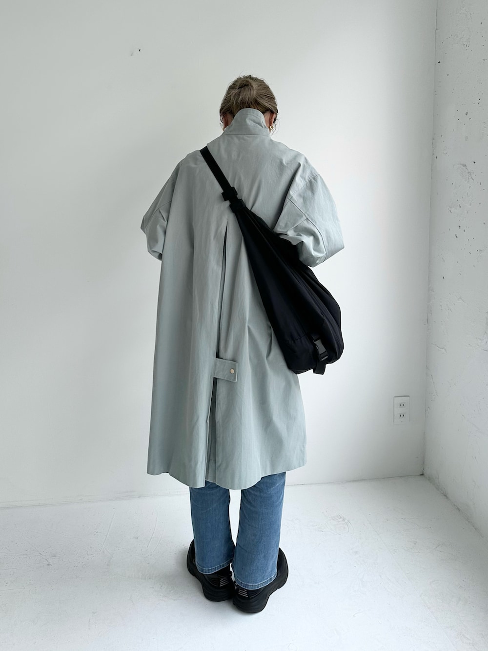 ブルー系のステンカラーコート、ブルー系のデニムパンツ、ブラック系のショルダーバッグを着用したレディースの冬コーディネートの3枚目の写真