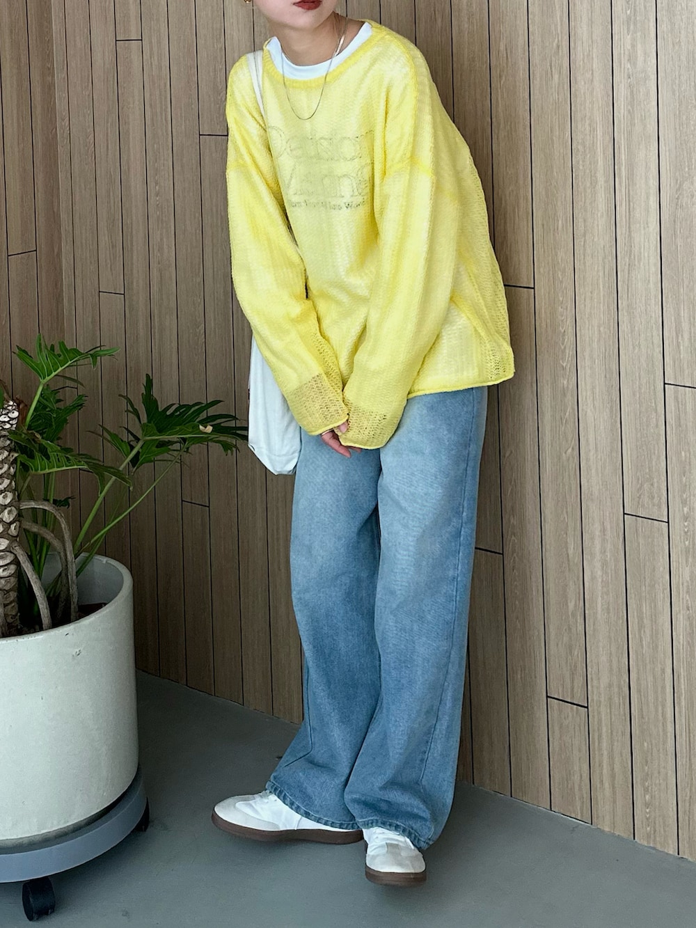 ホワイト系のスウェット、イエロー系のニット/セーター、ブルー系のデニムパンツを着用したレディースの春コーディネートの4枚目の写真