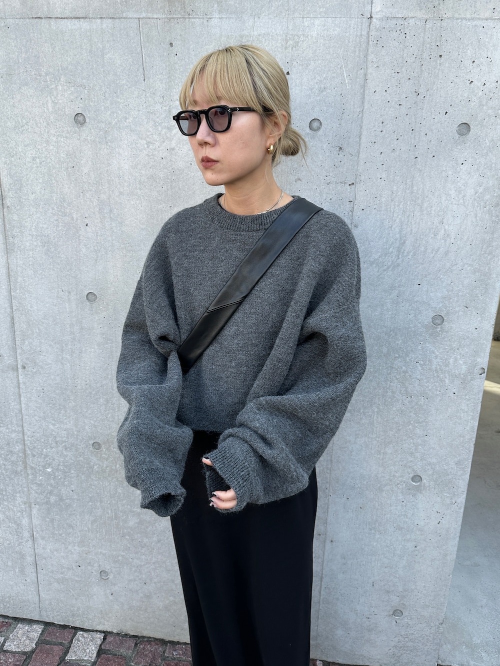 グレー系のニット/セーター、ブラック系のワンピース、ブラック系のショルダーバッグを着用したレディースの秋コーディネートの2枚目の写真