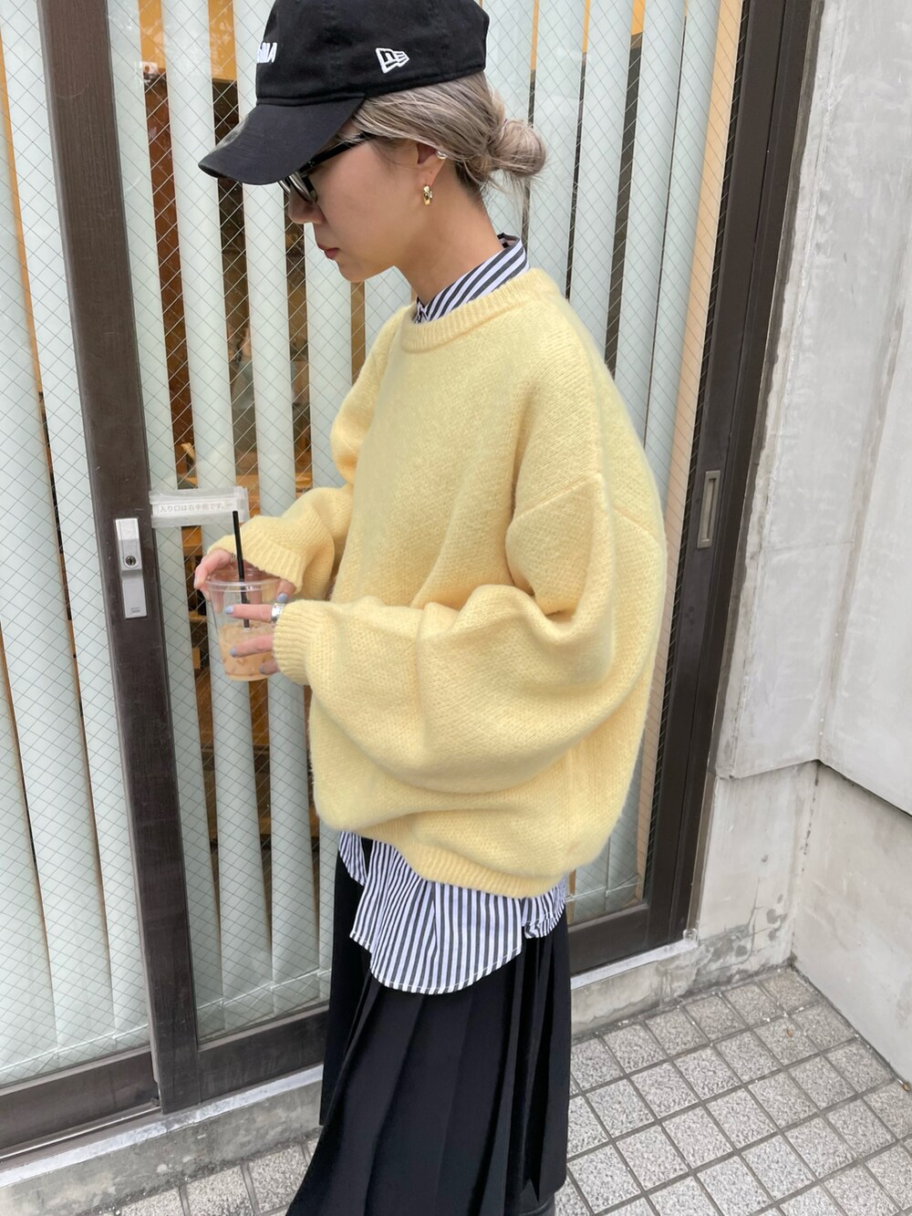 ブラック系のスカート、イエロー系のニット/セーター、ブラック系のシャツ/ブラウスを着用したレディースの冬コーディネートの3枚目の写真