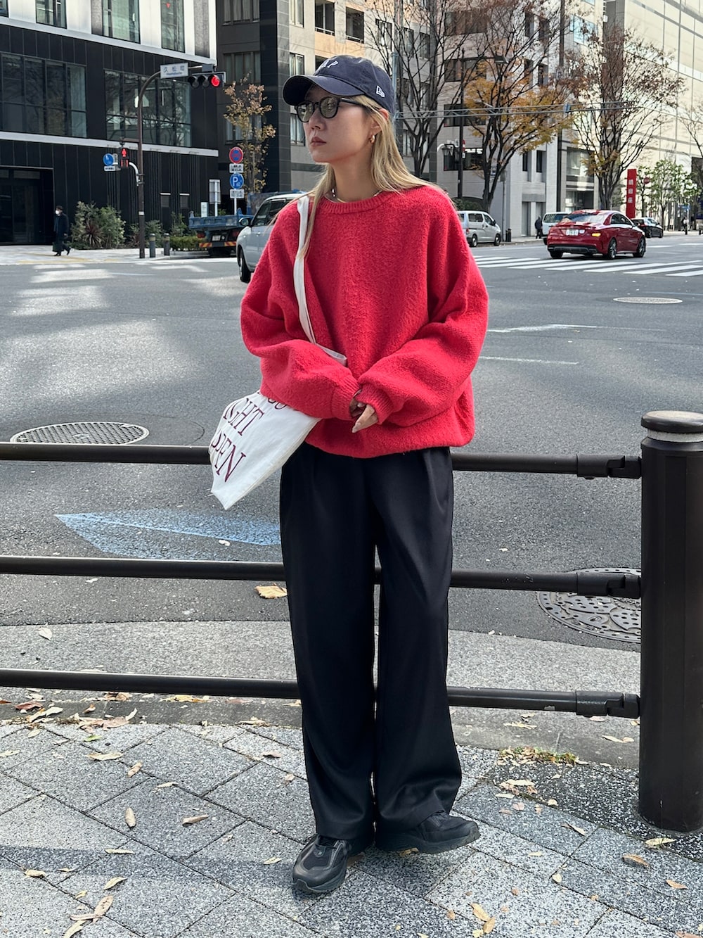 レッド系のニット/セーター、ホワイト系のTシャツ/カットソー、ブラック系のスラックスを着用したレディースの冬コーディネートの3枚目の写真