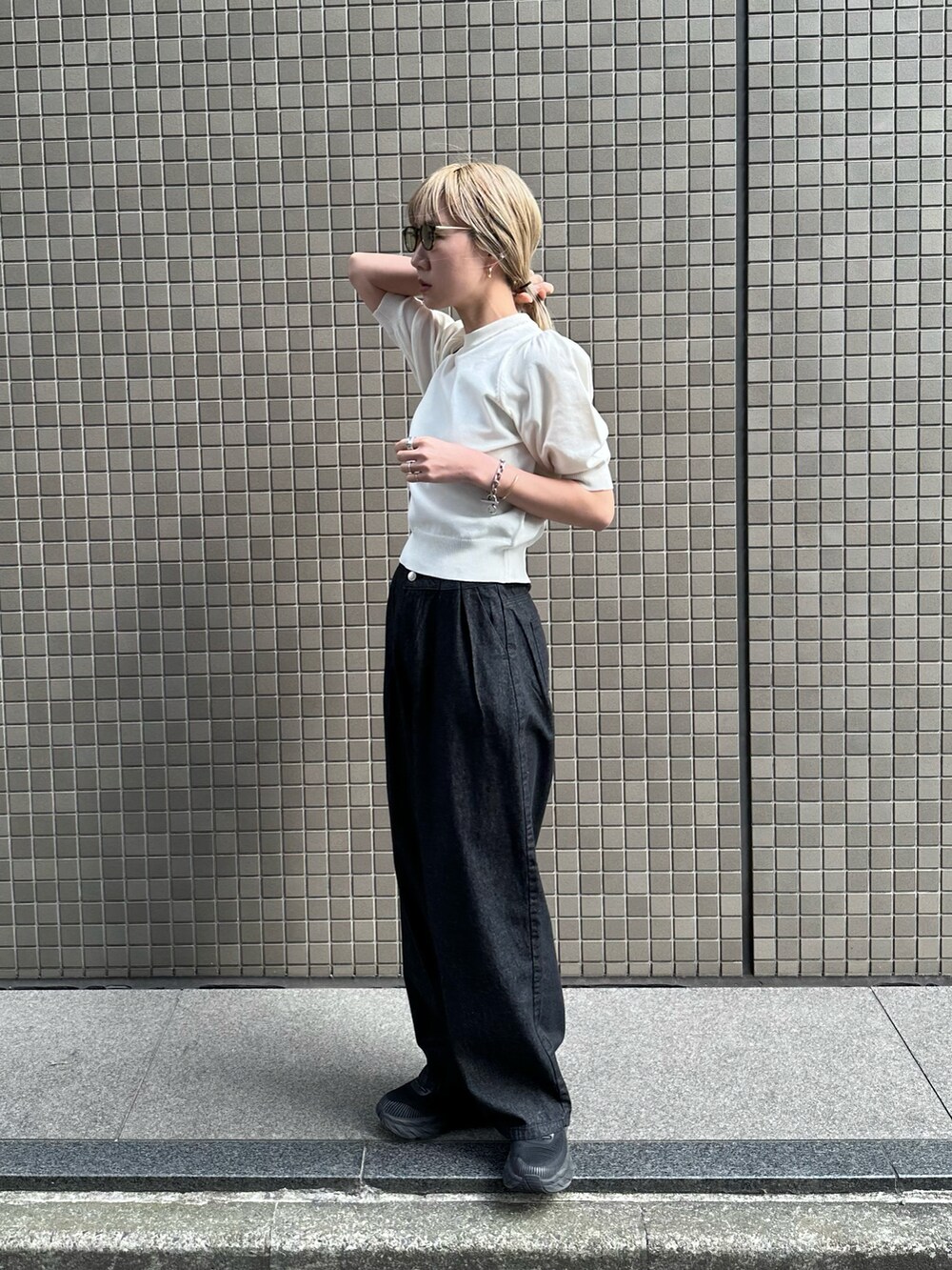 ホワイト系のニット/セーター、ブラック系のデニムパンツ、ブラック系のスニーカーを着用したレディースの春コーディネートの2枚目の写真