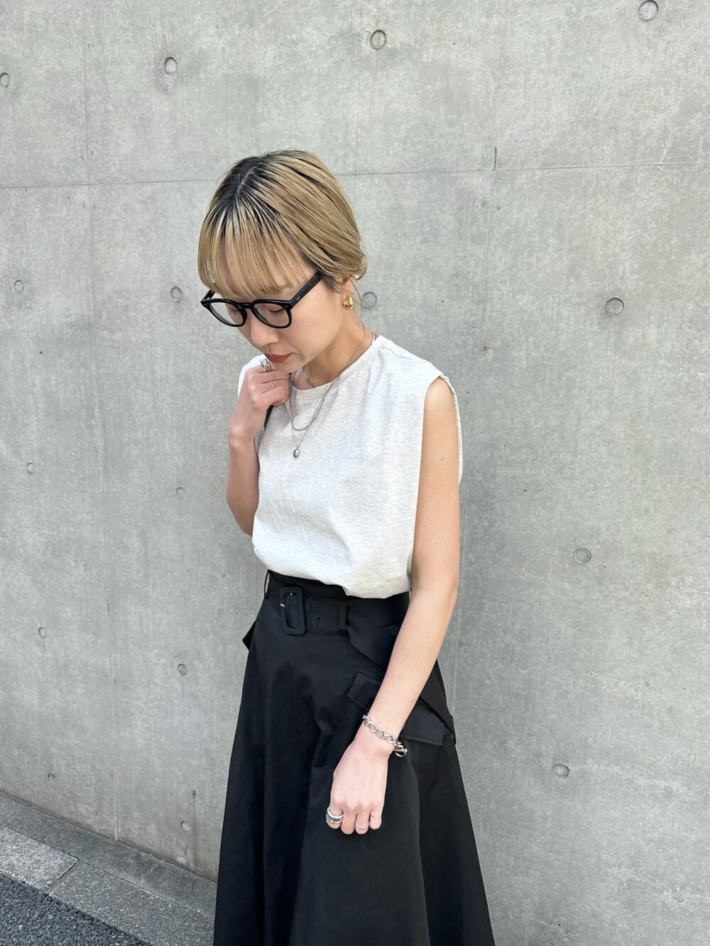 ブラック系のスカート、ホワイト系のミリタリージャケット、ベージュ系のタンクトップを着用したレディースの春コーディネートの5枚目の写真