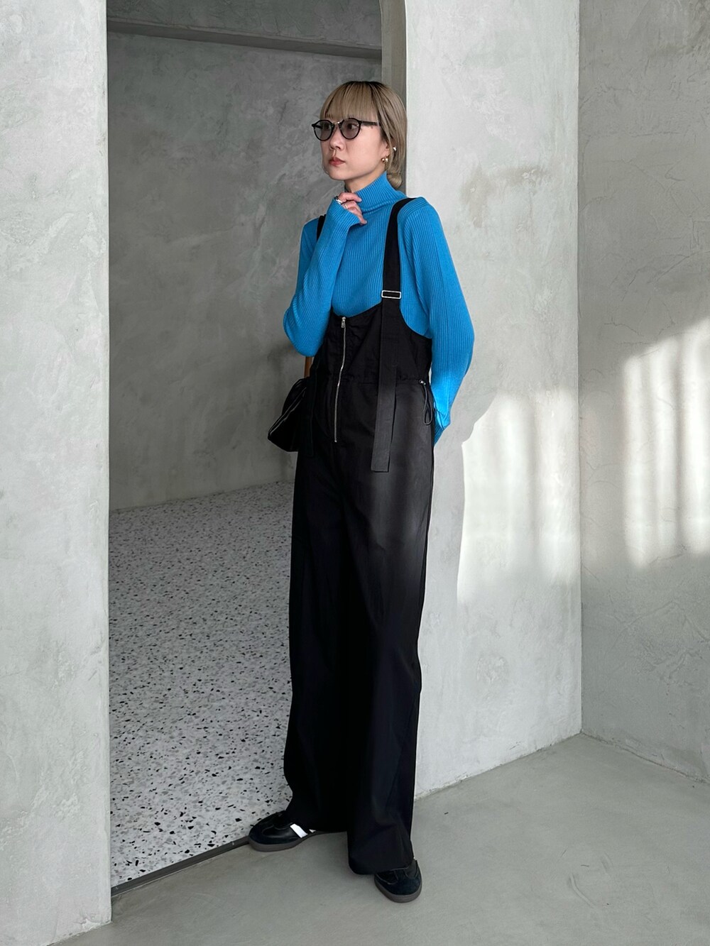 ブラック系のダウンジャケット/コート、ブルー系のニット/セーター、ブラック系のサロペット/オーバーオールを着用したレディースの秋コーディネートの4枚目の写真