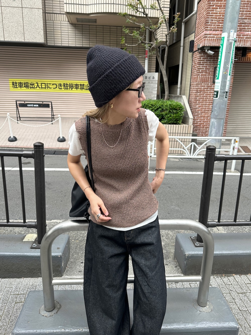 ブラウン系のタンクトップ、ブラック系のデニムパンツ、ホワイト系のTシャツ/カットソーを着用したレディースの夏コーディネートの4枚目の写真