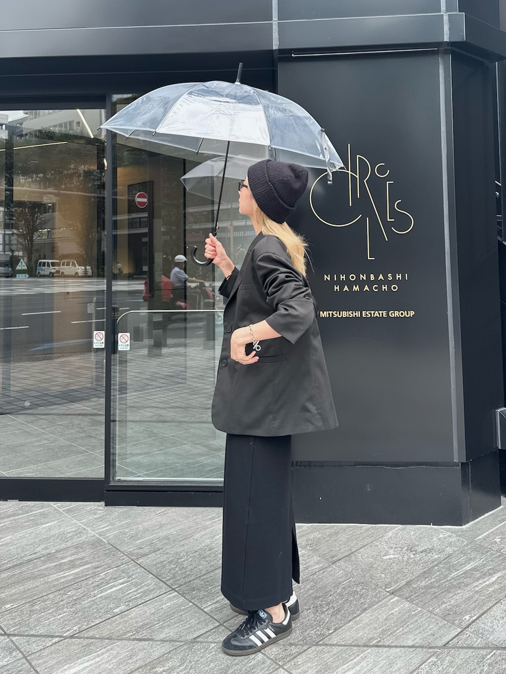 ブラック系のテーラードジャケット、ブラック系のワンピース、ブラック系のスニーカーを着用したレディースの秋コーディネートの2枚目の写真