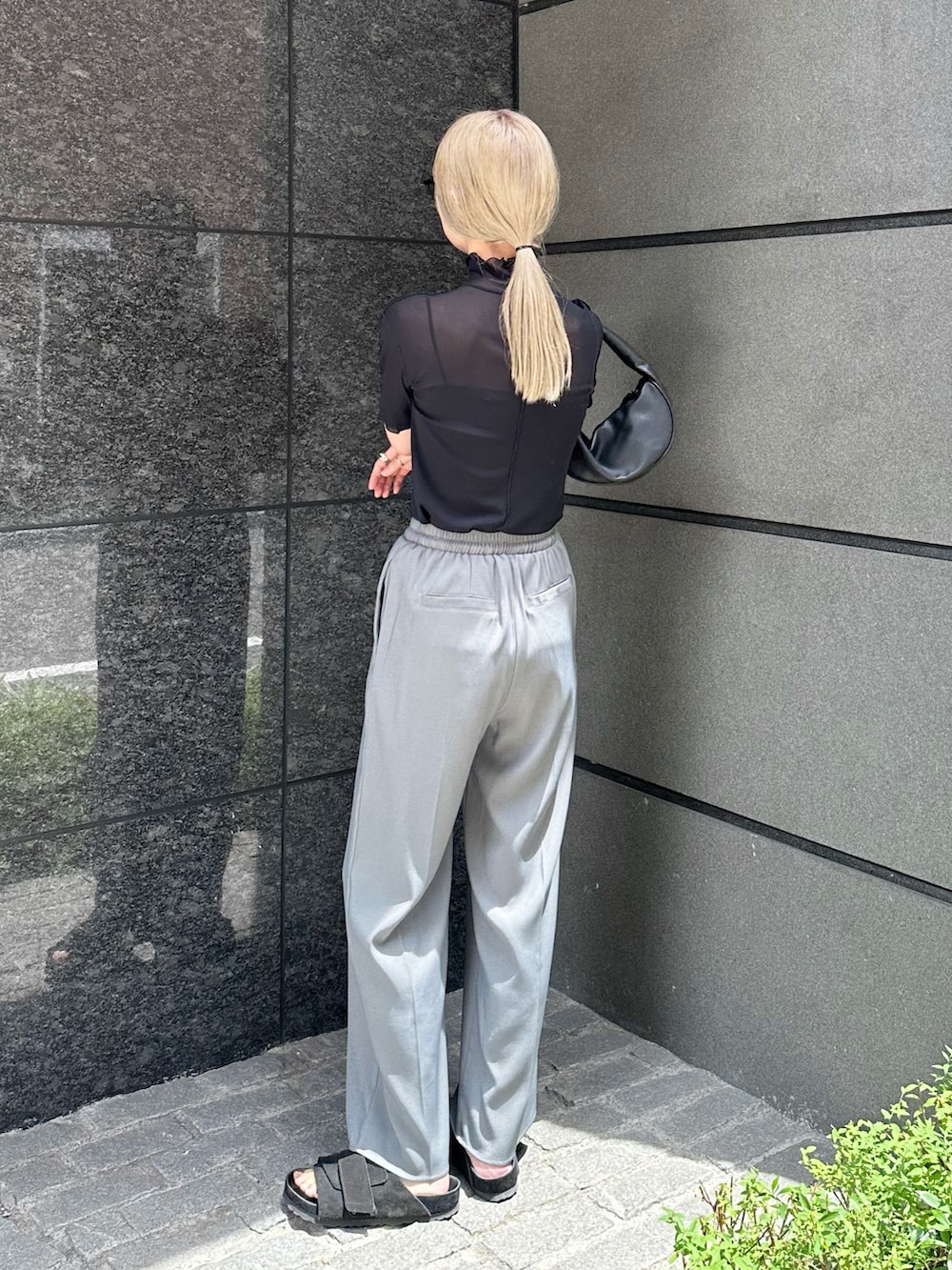 グレー系のスラックス、ブラック系のTシャツ/カットソー、ブラック系のハンドバッグを着用したレディースの夏コーディネートの3枚目の写真