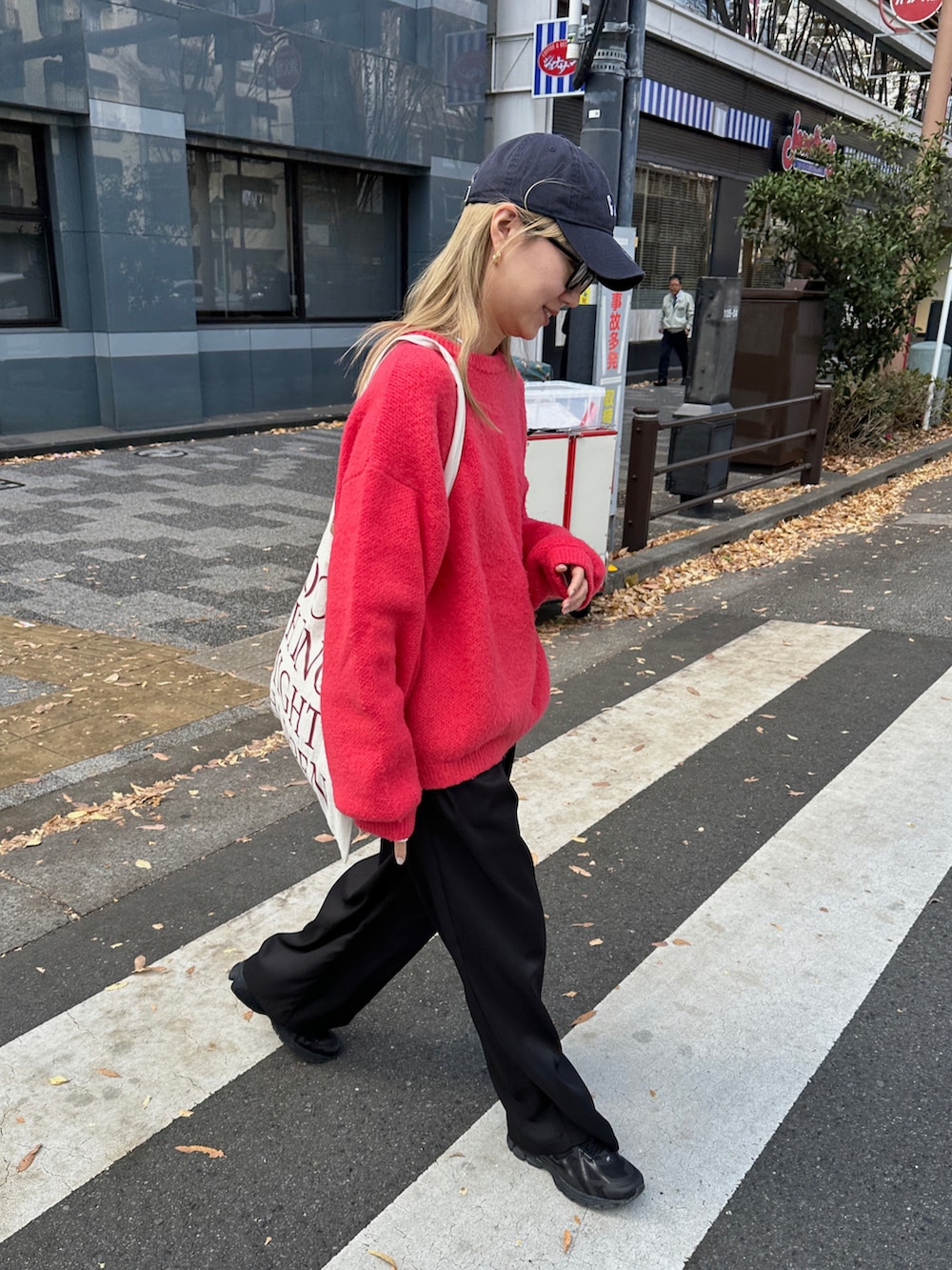 レッド系のニット/セーター、ホワイト系のTシャツ/カットソー、ブラック系のスラックスを着用したレディースの冬コーディネートの4枚目の写真