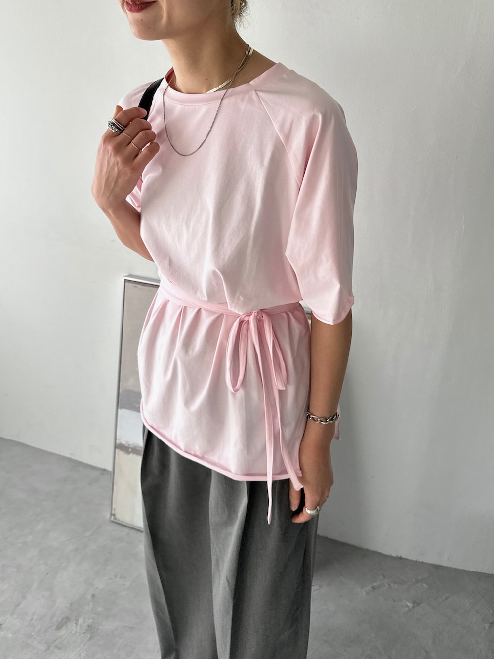 ピンク系のTシャツ/カットソー、グレー系のスラックス、ブラック系のサンダルを着用したレディースの夏コーディネートの2枚目の写真