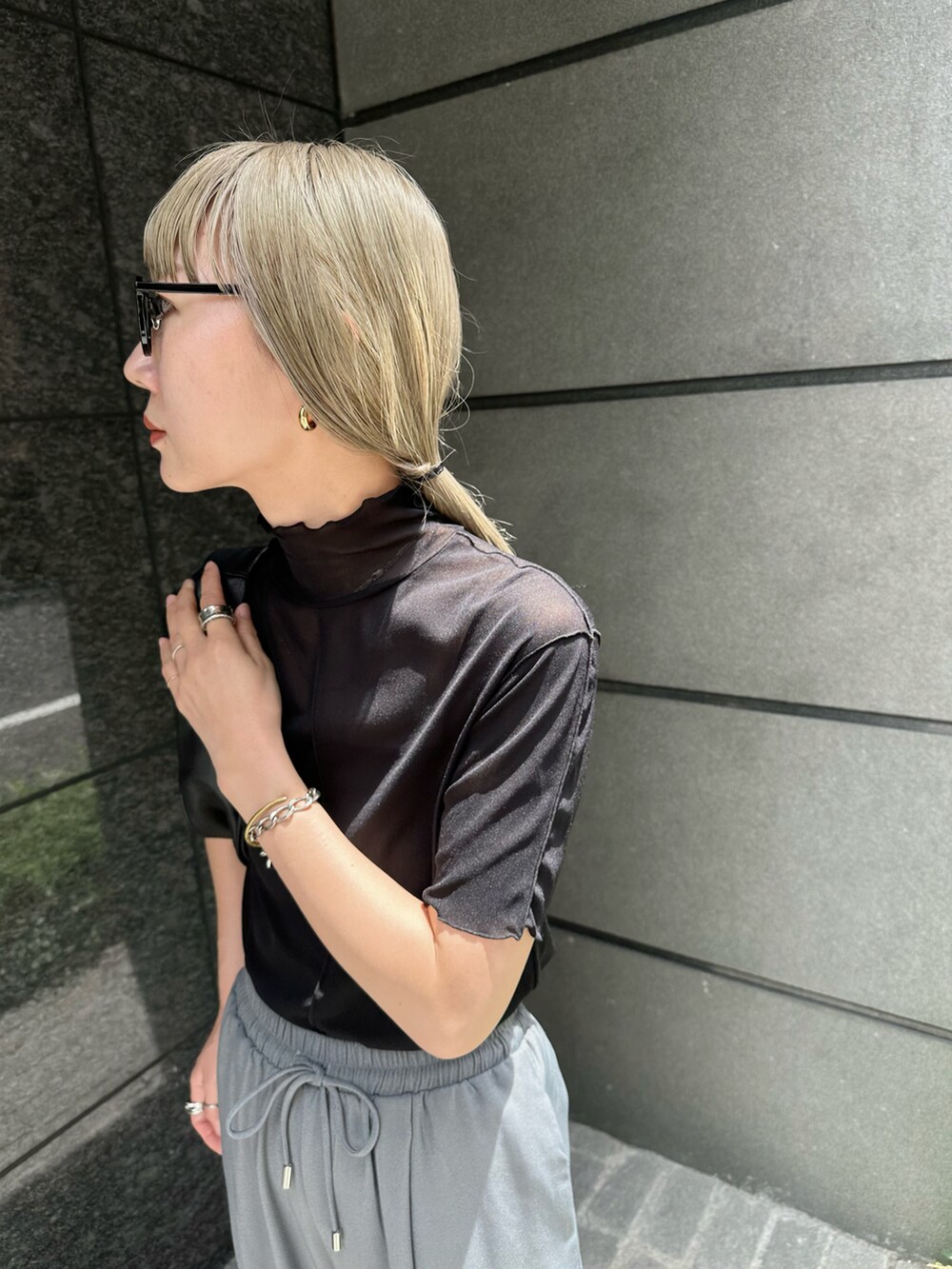 グレー系のスラックス、ブラック系のTシャツ/カットソー、ブラック系のハンドバッグを着用したレディースの夏コーディネートの5枚目の写真