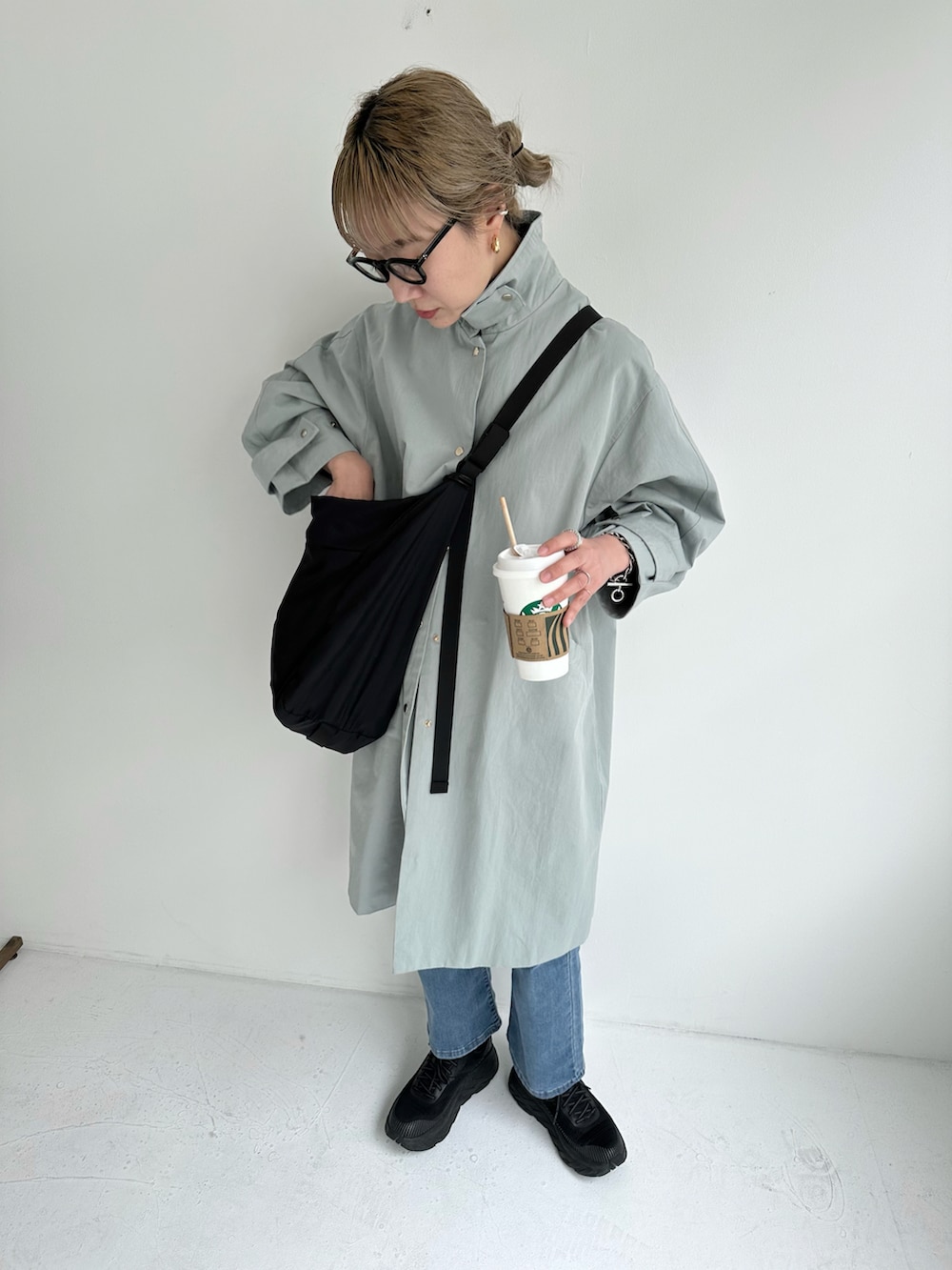 ブルー系のステンカラーコート、ブルー系のデニムパンツ、ブラック系のショルダーバッグを着用したレディースの冬コーディネートの5枚目の写真