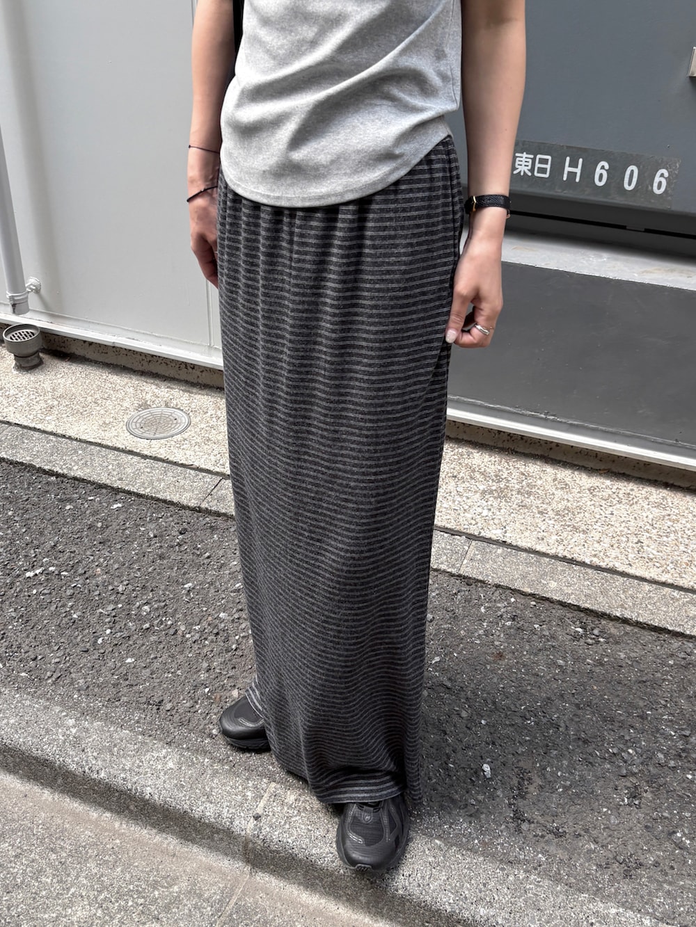 グレー系のスカート、ブルー系のTシャツ/カットソー、ブラック系のトートバッグを着用したレディースの夏コーディネートの5枚目の写真