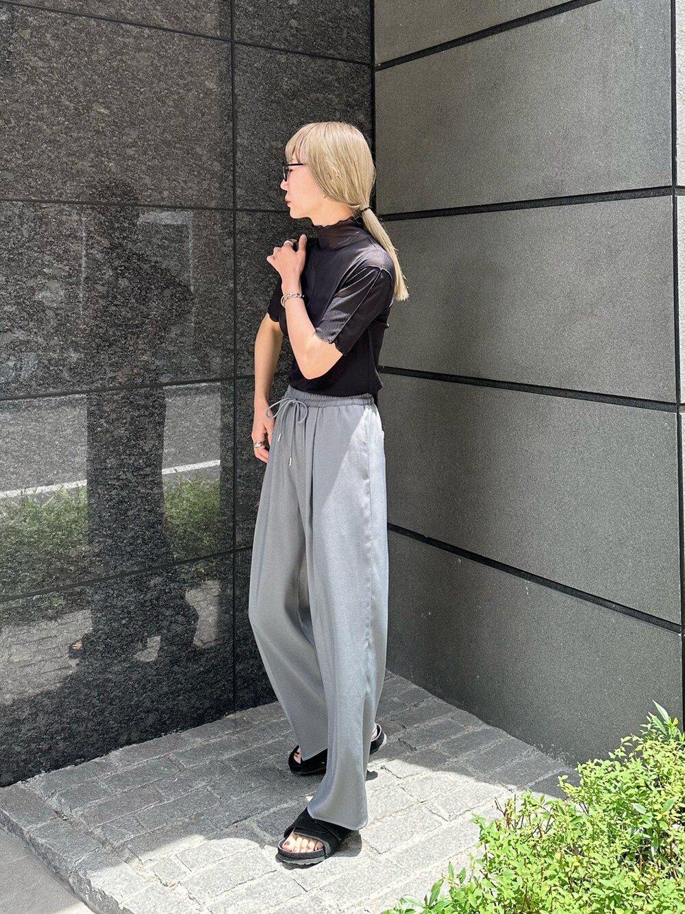 グレー系のスラックス、ブラック系のTシャツ/カットソー、ブラック系のハンドバッグを着用したレディースの夏コーディネートの2枚目の写真