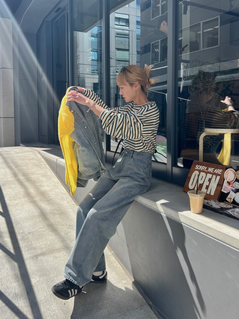 ブルー系のデニムジャケット、ブルー系のデニムパンツ、イエロー系のニット/セーターを着用したレディースの春コーディネートの4枚目の写真