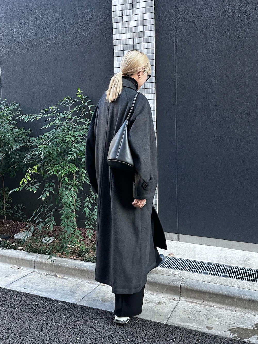 グレー系のステンカラーコート、グリーン系のスニーカー、ブラック系のショルダーバッグを着用したレディースの冬コーディネートの2枚目の写真