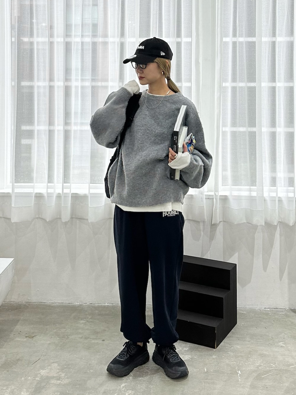 グレー系のニット/セーター、ホワイト系のTシャツ/カットソー、ブルー系のスウェットパンツを着用したレディースの秋コーディネートの2枚目の写真