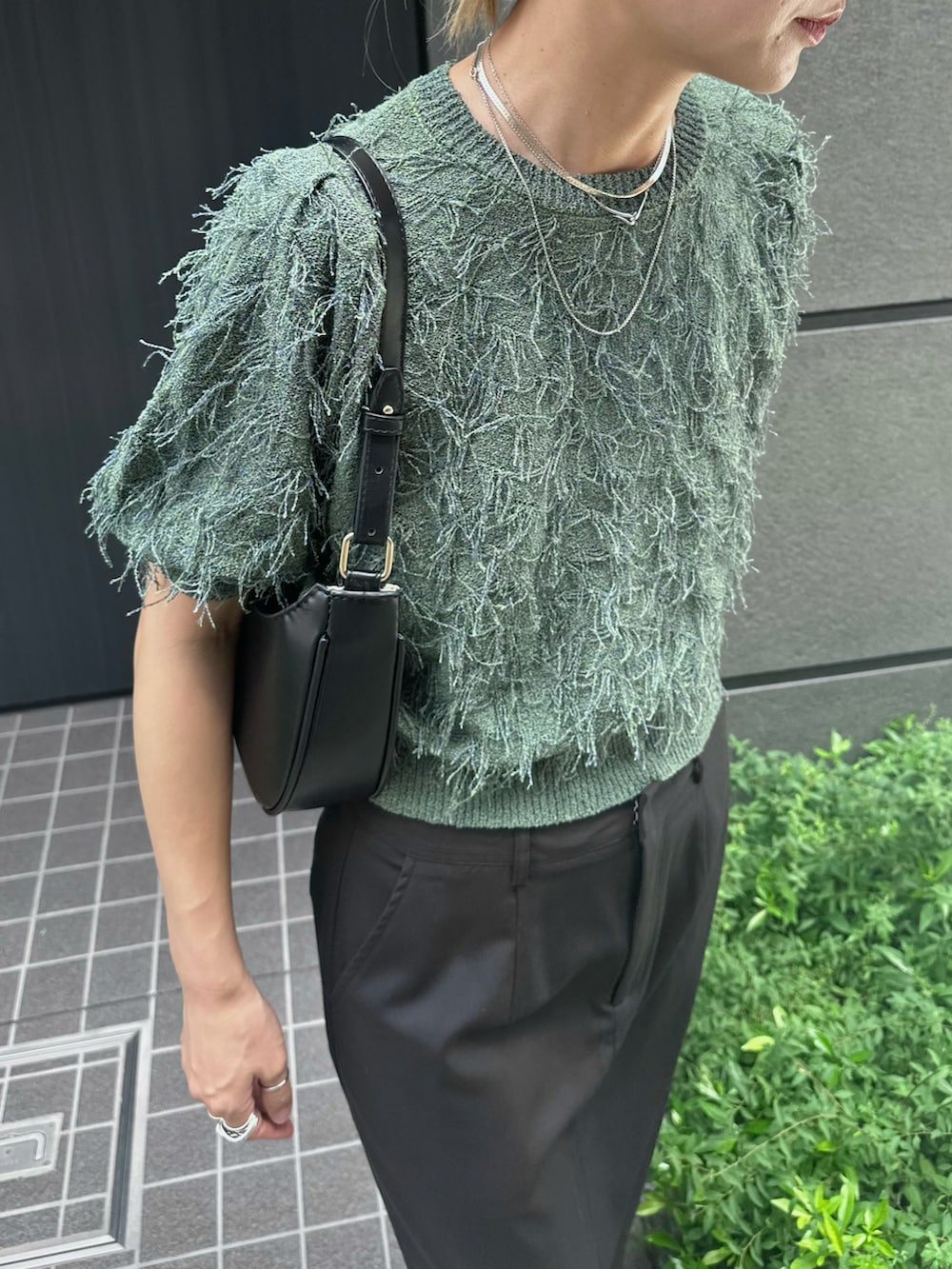 グリーン系のニット/セーター、ブラック系のスカート、ブラック系のスリッポンを着用したレディースの夏コーディネートの4枚目の写真