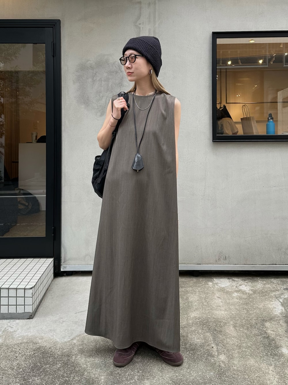 グレー系のワンピース、ブラウン系のスニーカー、ブラック系のバックパック/リュックを着用したレディースの春コーディネートの4枚目の写真