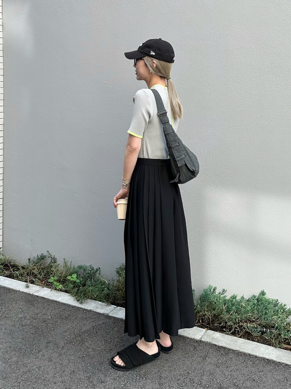 グレー系のニット/セーター、ブラック系のスカート、ブラック系のサンダルを着用したレディースの夏コーディネートの2枚目の写真