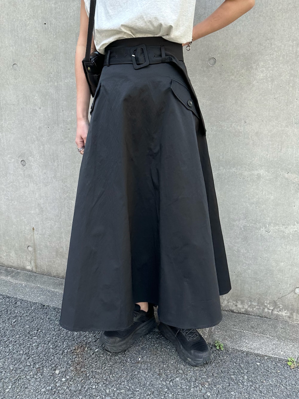 ブラック系のスカート、ホワイト系のミリタリージャケット、ベージュ系のタンクトップを着用したレディースの春コーディネートの4枚目の写真