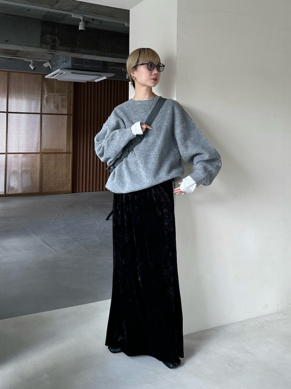 グレー系のニット/セーター、ベージュ系のTシャツ/カットソー、ブラック系のスカートを着用したレディースの秋コーディネートの2枚目の写真