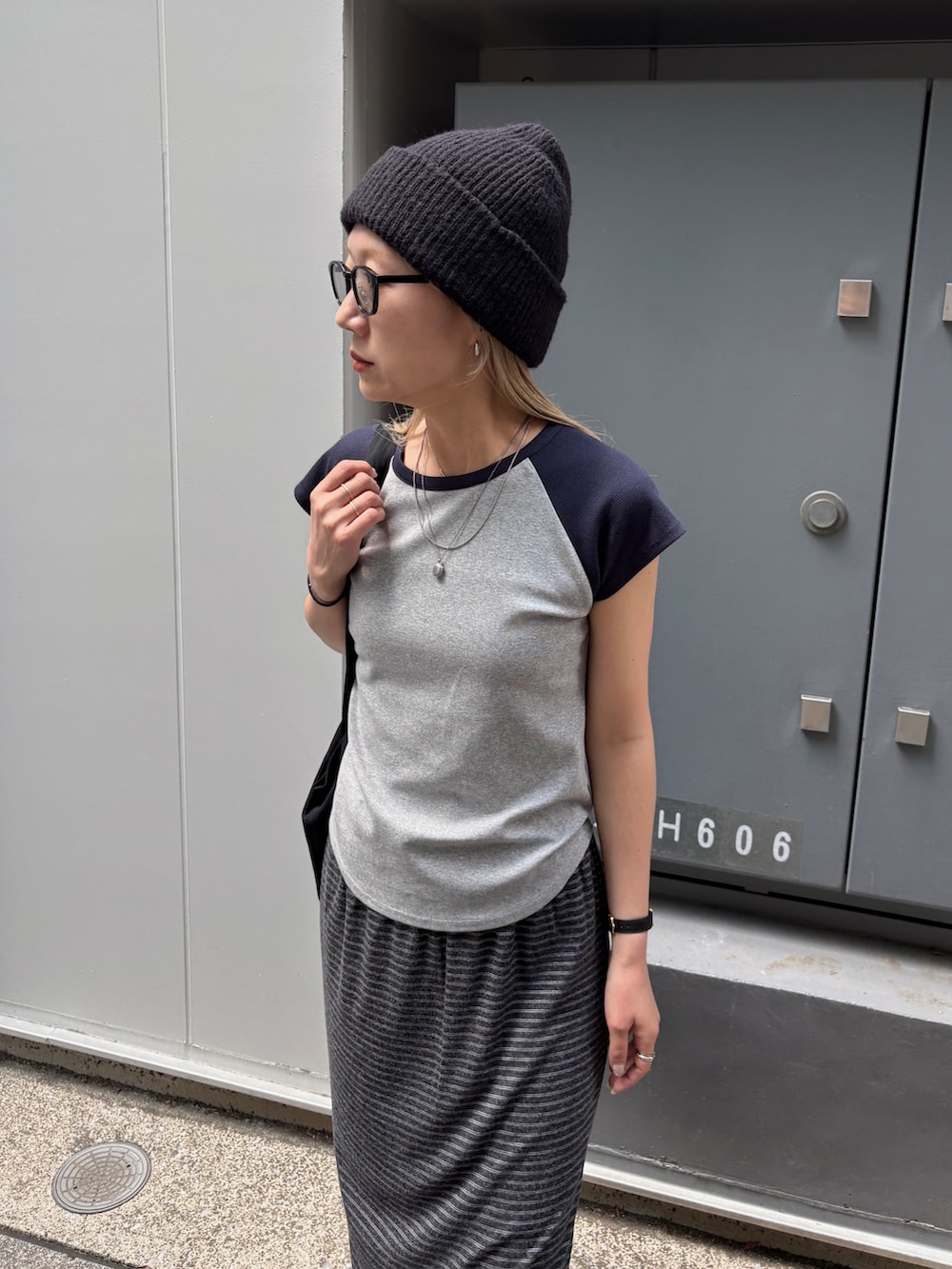 グレー系のスカート、ブルー系のTシャツ/カットソー、ブラック系のトートバッグを着用したレディースの夏コーディネートの4枚目の写真