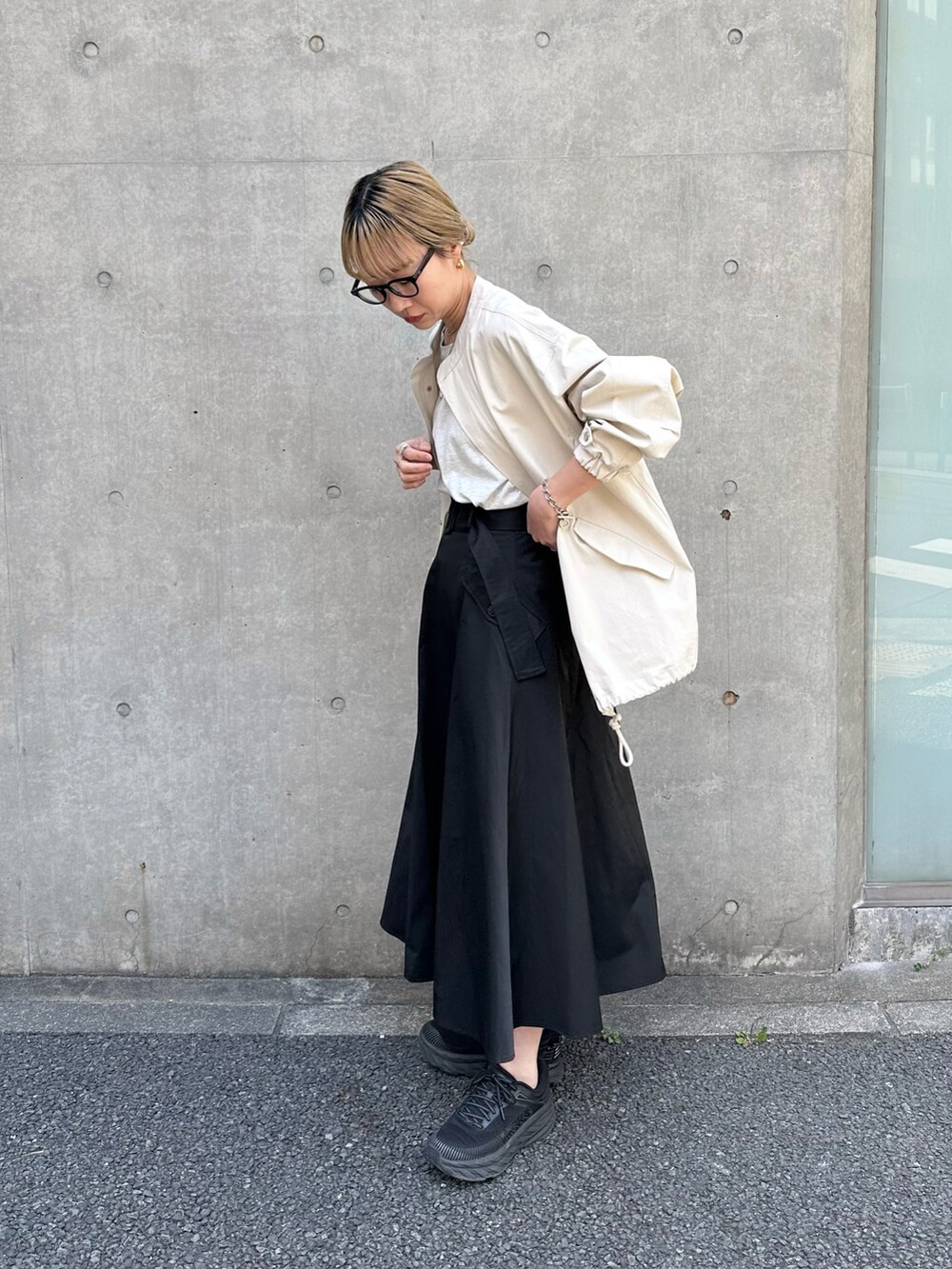 ブラック系のスカート、ホワイト系のミリタリージャケット、ベージュ系のタンクトップを着用したレディースの春コーディネートの2枚目の写真