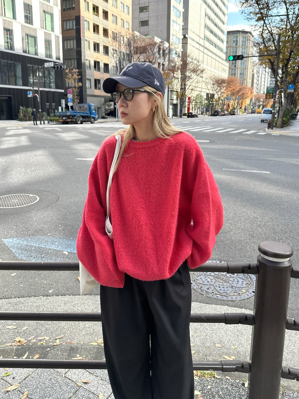 レッド系のニット/セーター、ホワイト系のTシャツ/カットソー、ブラック系のスラックスを着用したレディースの冬コーディネートの5枚目の写真