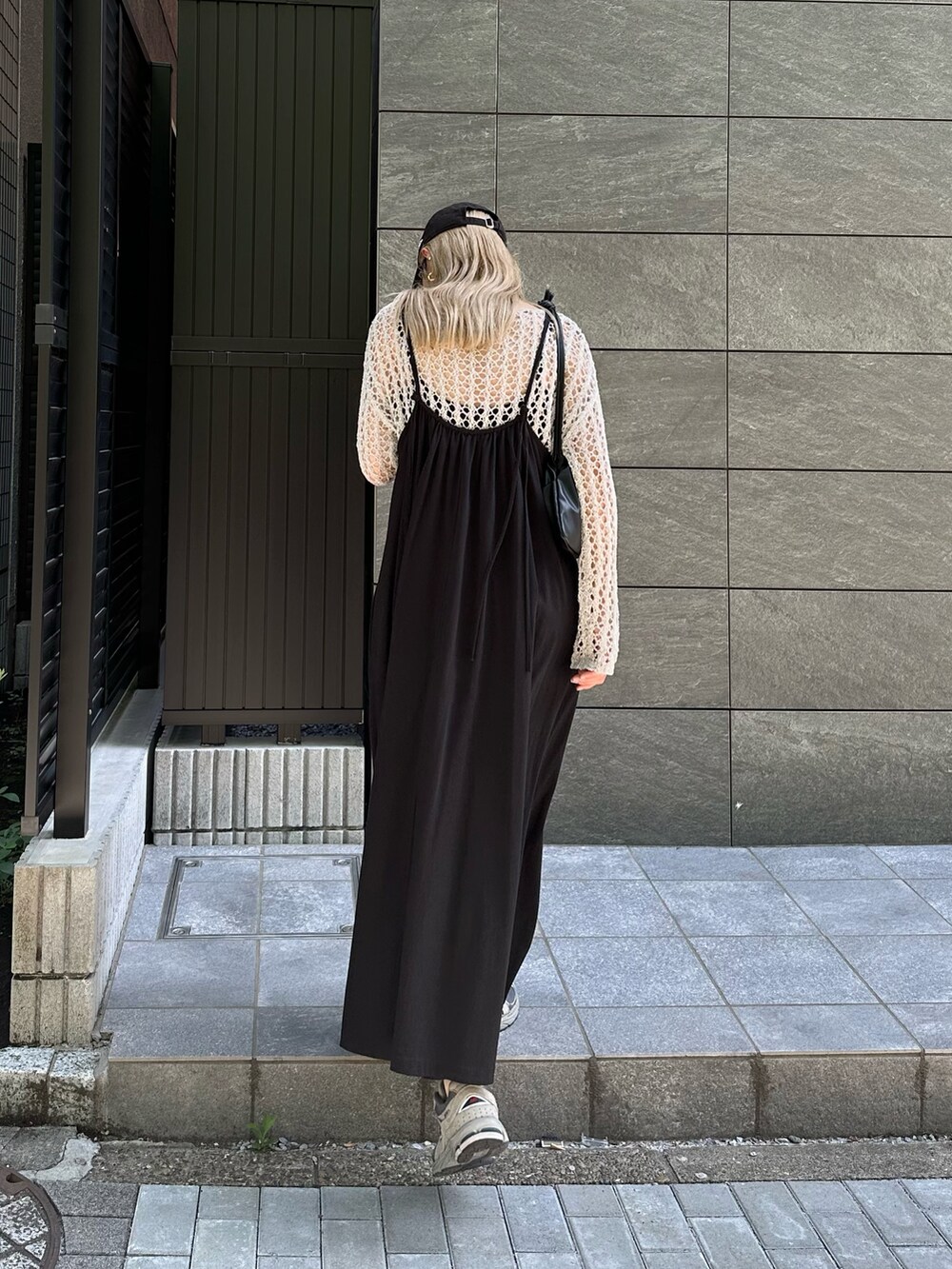 ホワイト系のニット/セーター、ブラック系のワンピース、グレー系のスニーカーを着用したレディースの夏コーディネートの2枚目の写真