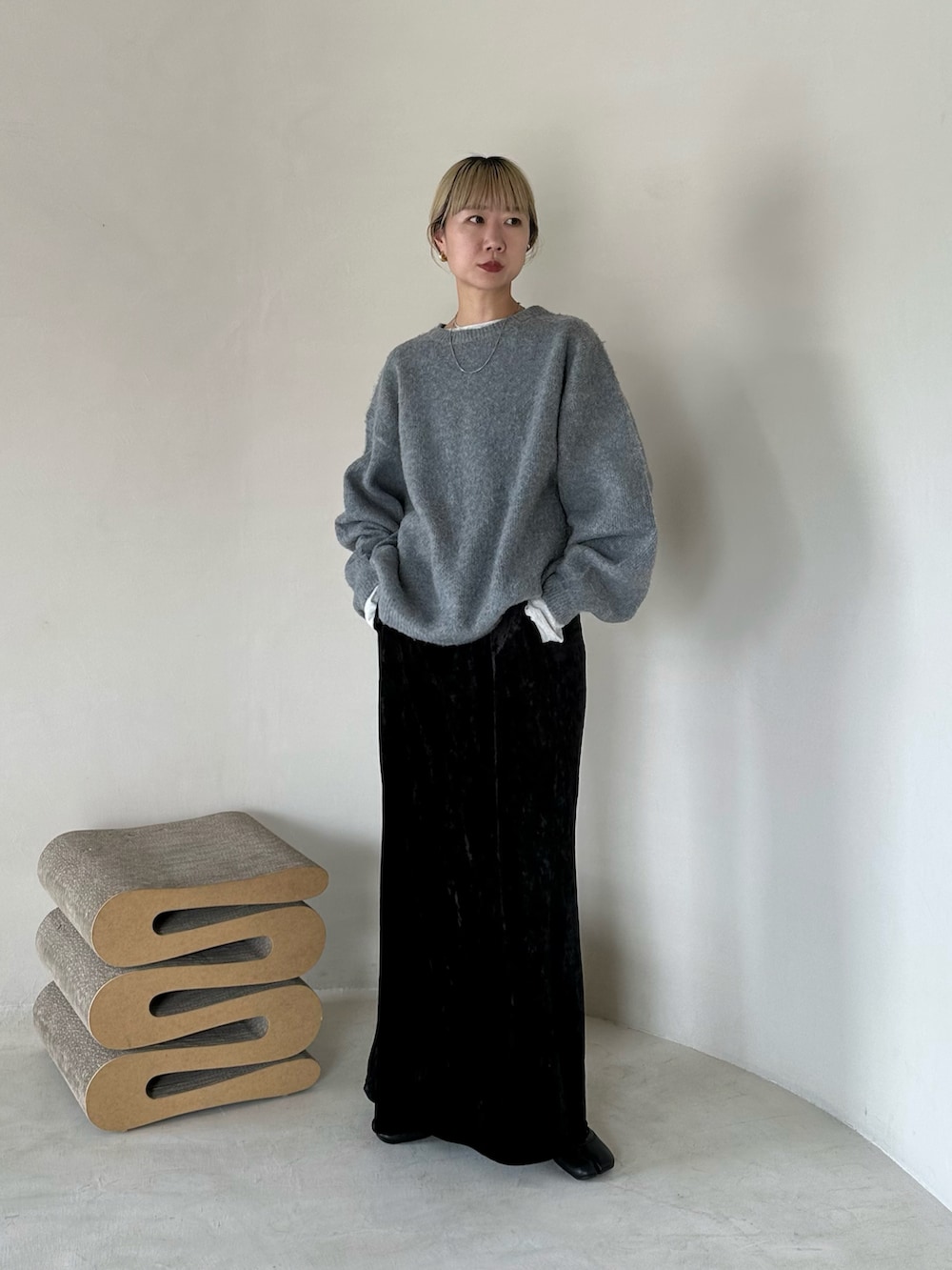 グレー系のニット/セーター、ベージュ系のTシャツ/カットソー、ブラック系のスカートを着用したレディースの秋コーディネートの3枚目の写真