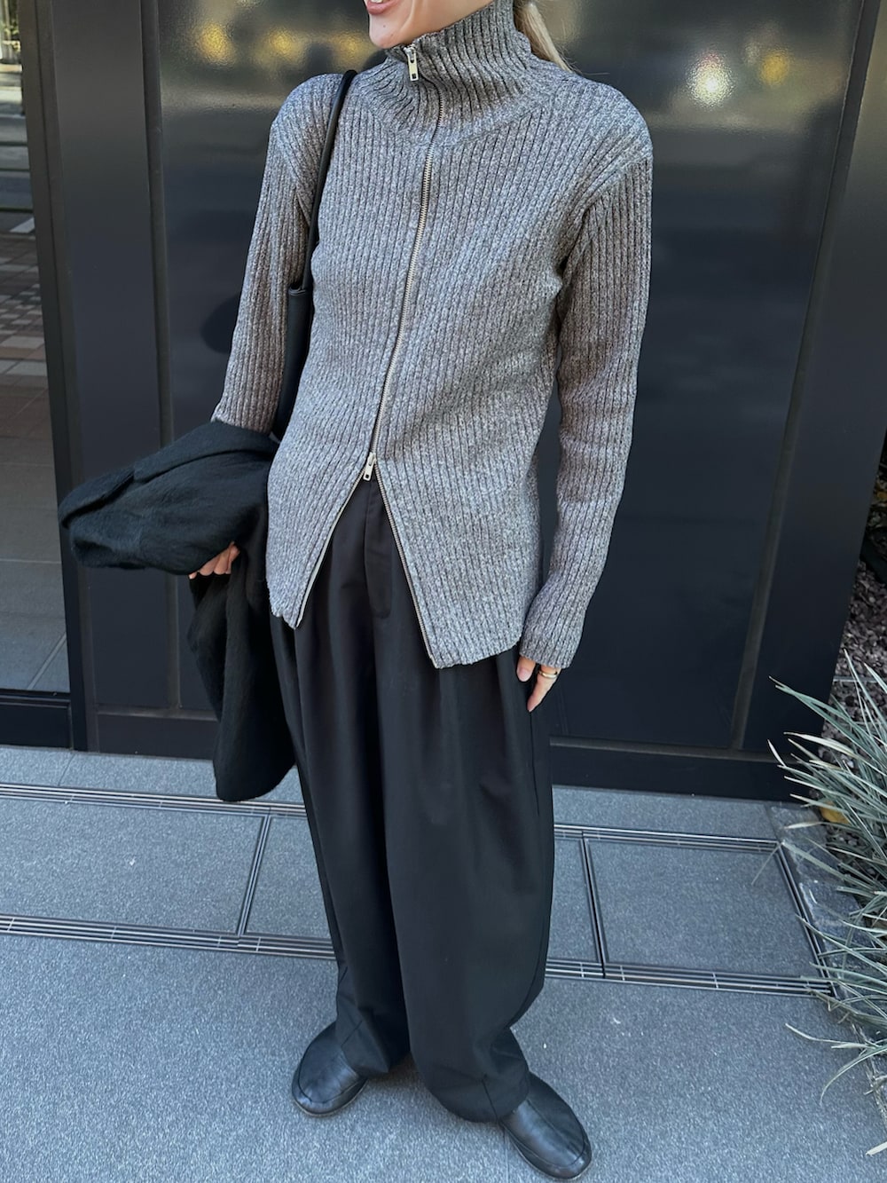 グレー系のニット/セーター、ブラック系のスラックス、ブラック系のバレエシューズを着用したレディースの冬コーディネートの3枚目の写真